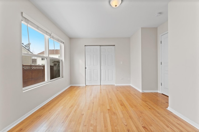 unfurnished bedroom with baseboards, a closet, and light wood-style floors