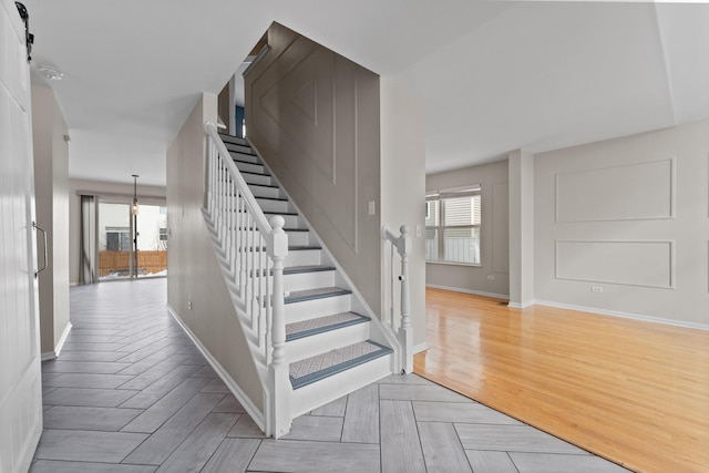 stairway with a healthy amount of sunlight, parquet flooring, and baseboards