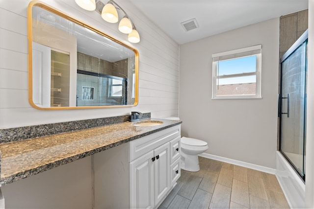 full bathroom with wood finish floors, toilet, enclosed tub / shower combo, vanity, and baseboards