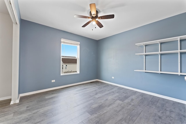 spare room featuring a ceiling fan, baseboards, and wood finished floors