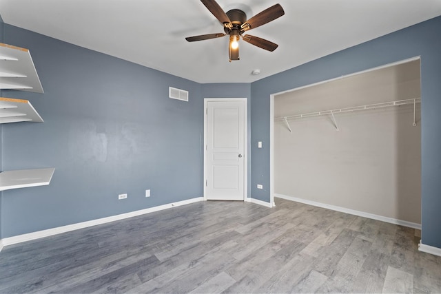 unfurnished bedroom featuring baseboards, visible vents, ceiling fan, light wood-style floors, and a closet