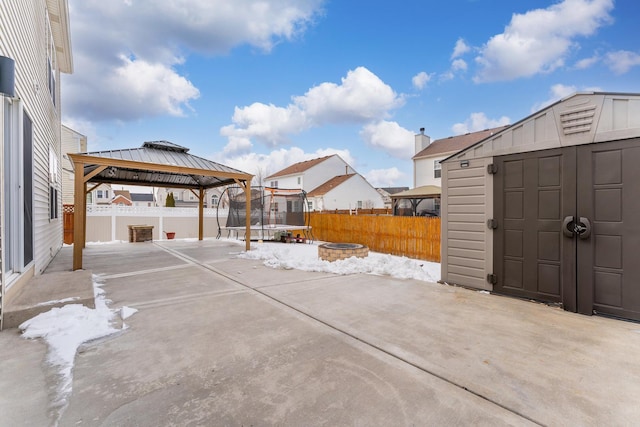 view of patio / terrace featuring a trampoline, an outbuilding, a gazebo, a storage shed, and an outdoor fire pit