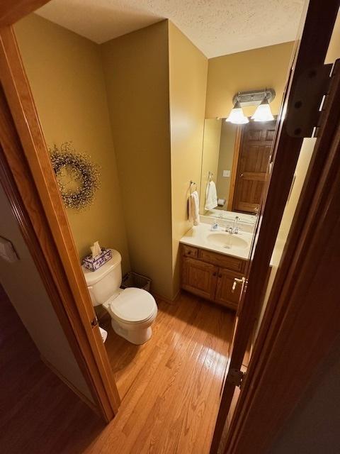 bathroom featuring toilet, a textured ceiling, vanity, and wood-type flooring