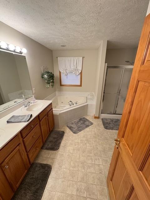 bathroom featuring shower with separate bathtub, vanity, and a textured ceiling