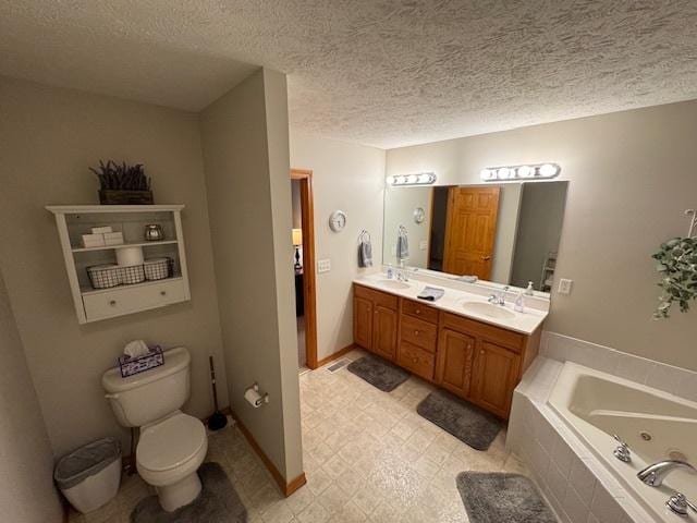 bathroom with vanity, a textured ceiling, a relaxing tiled tub, and toilet