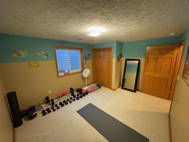 exercise room featuring a textured ceiling and carpet