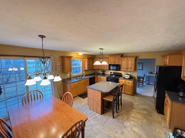 kitchen with a center island, pendant lighting, a notable chandelier, black appliances, and sink