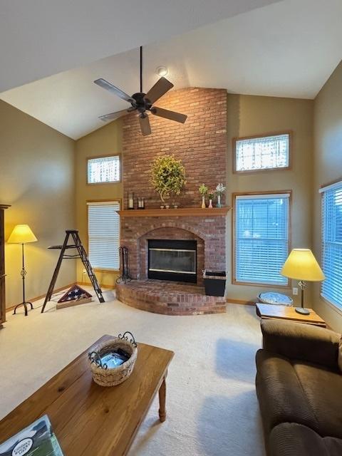 carpeted living room featuring high vaulted ceiling, ceiling fan, and a fireplace