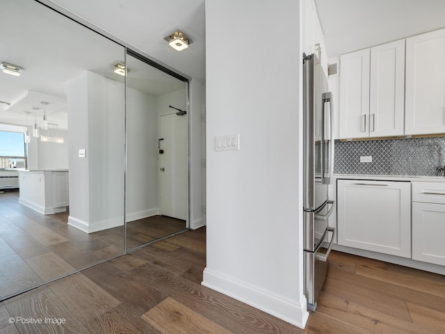 interior space with stainless steel refrigerator, white cabinetry, dark wood-type flooring, and tasteful backsplash