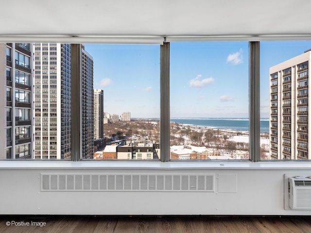 unfurnished sunroom with a water view, radiator heating unit, and a wall mounted air conditioner