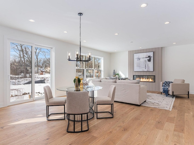 dining space featuring an inviting chandelier, light hardwood / wood-style flooring, and a large fireplace