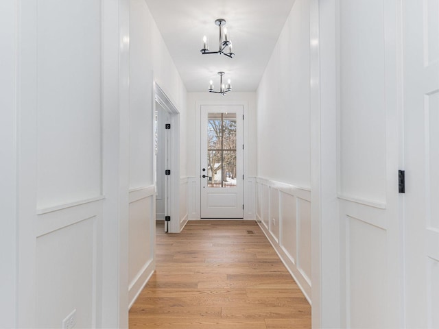 doorway to outside with light hardwood / wood-style floors and a chandelier