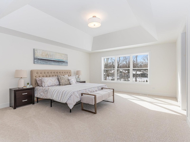 bedroom with a raised ceiling and light colored carpet