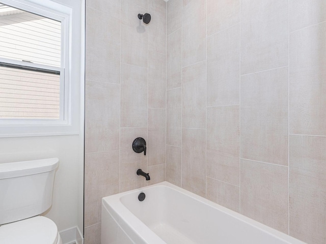 bathroom featuring tiled shower / bath combo and toilet