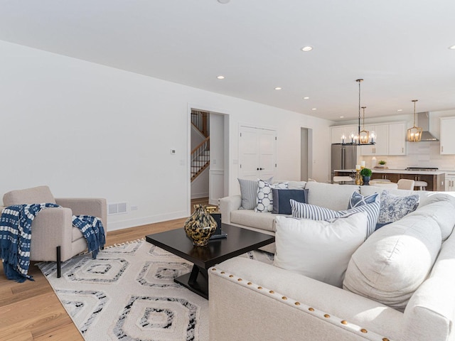 living room with light hardwood / wood-style floors and a notable chandelier