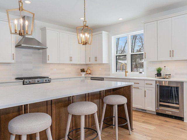 kitchen featuring a kitchen bar, white cabinets, beverage cooler, and range