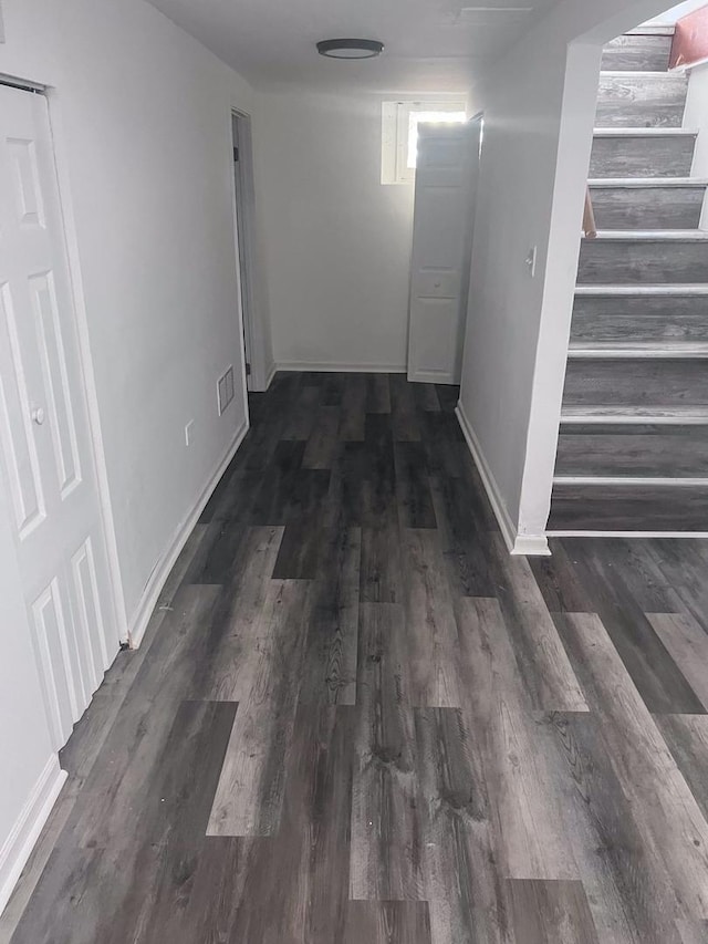 hall featuring stairs, dark wood-style floors, visible vents, and baseboards