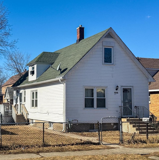 rear view of house featuring a fenced front yard, a gate, and a shingled roof