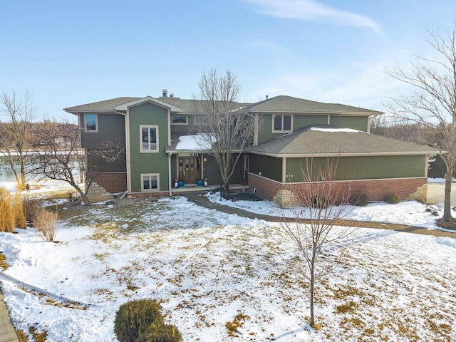 snow covered property featuring brick siding and a sunroom