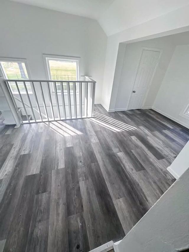 unfurnished room with lofted ceiling, dark wood-style floors, baseboards, and a wealth of natural light