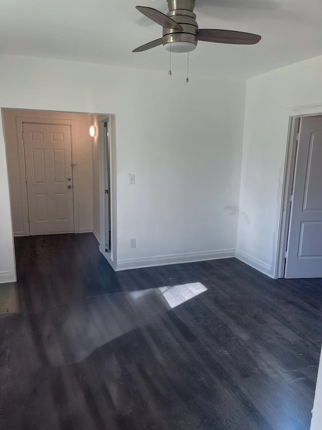 spare room with dark wood-style floors, baseboards, and a ceiling fan