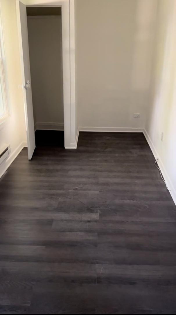 unfurnished bedroom with dark wood finished floors and baseboards