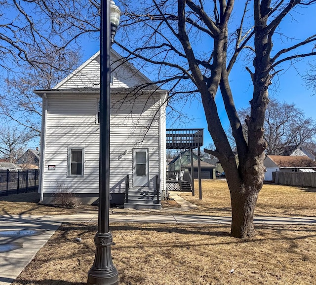 exterior space featuring entry steps, fence, and a front lawn