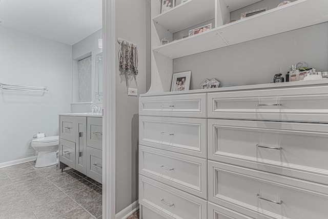 bathroom with toilet, baseboards, and vanity