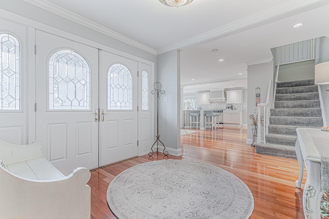 entryway featuring a wealth of natural light, stairway, and crown molding