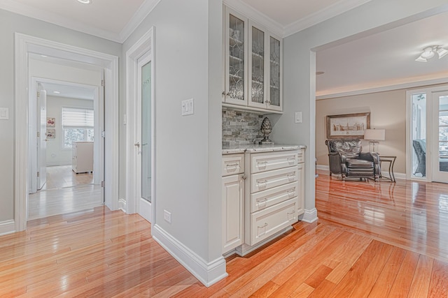 hallway featuring baseboards, light wood-style flooring, and crown molding