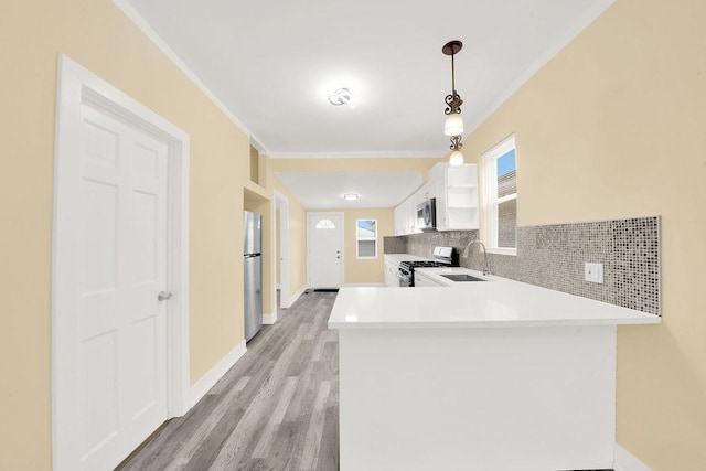 kitchen featuring stainless steel appliances, white cabinets, decorative light fixtures, sink, and kitchen peninsula