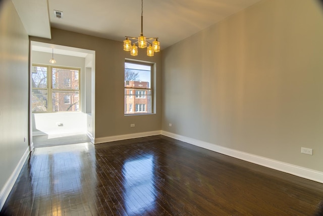 unfurnished room with plenty of natural light, dark hardwood / wood-style flooring, and a chandelier