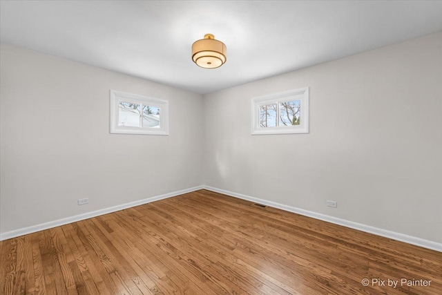 spare room featuring visible vents, baseboards, and wood finished floors