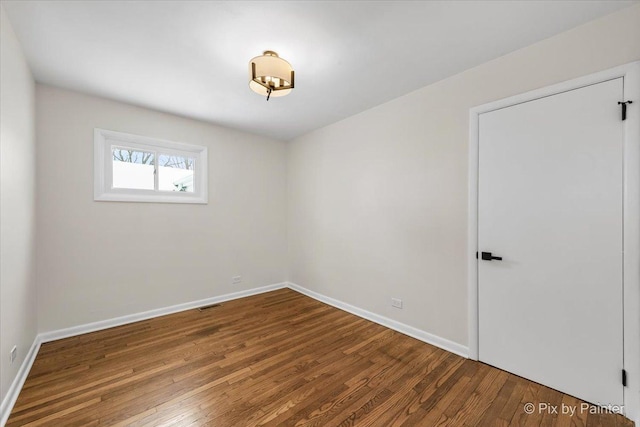 spare room featuring visible vents, baseboards, and wood finished floors