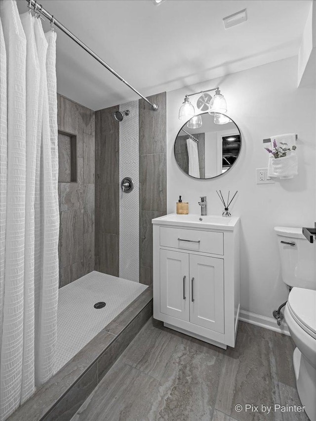 full bathroom with a stall shower, vanity, toilet, and baseboards