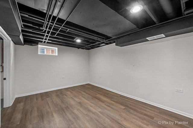 basement with visible vents, baseboards, and wood finished floors