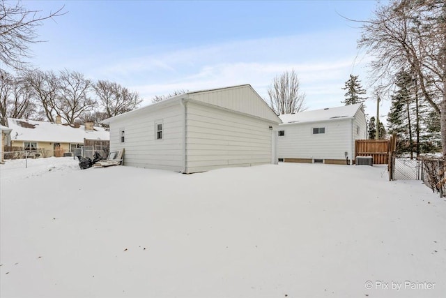 snow covered rear of property with a garage and fence