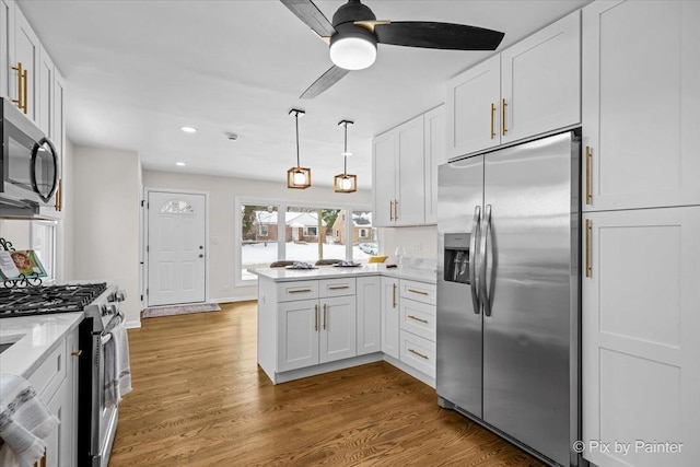 kitchen featuring recessed lighting, appliances with stainless steel finishes, white cabinets, wood finished floors, and a peninsula