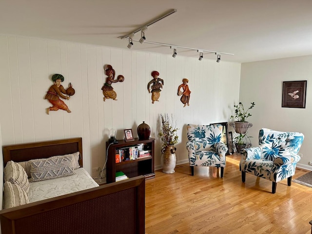 bedroom featuring rail lighting and wood finished floors