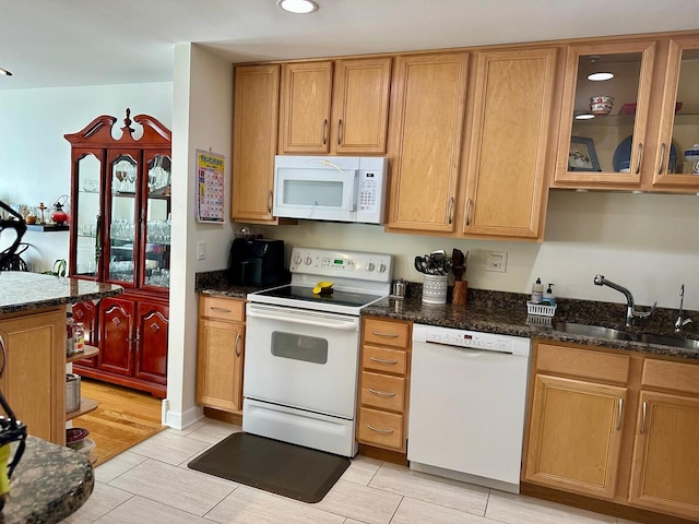 kitchen with white appliances, a sink, and dark stone countertops