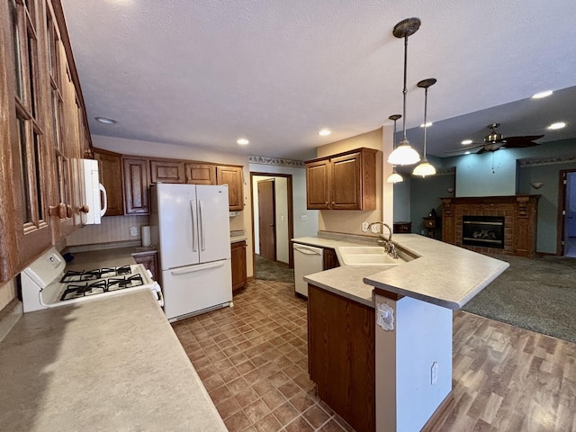 kitchen with white appliances, a kitchen breakfast bar, decorative light fixtures, a peninsula, and a sink