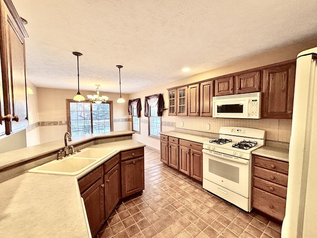 kitchen featuring light countertops, white appliances, a sink, and glass insert cabinets