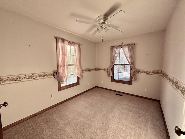 unfurnished room featuring baseboards, visible vents, ceiling fan, and light colored carpet