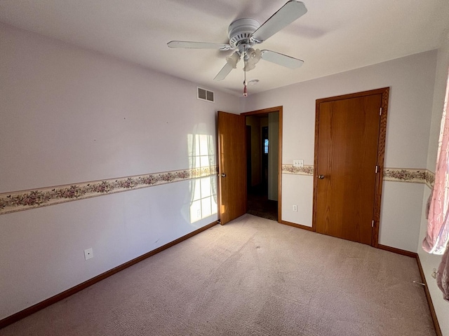 unfurnished bedroom featuring a ceiling fan, visible vents, light carpet, and baseboards