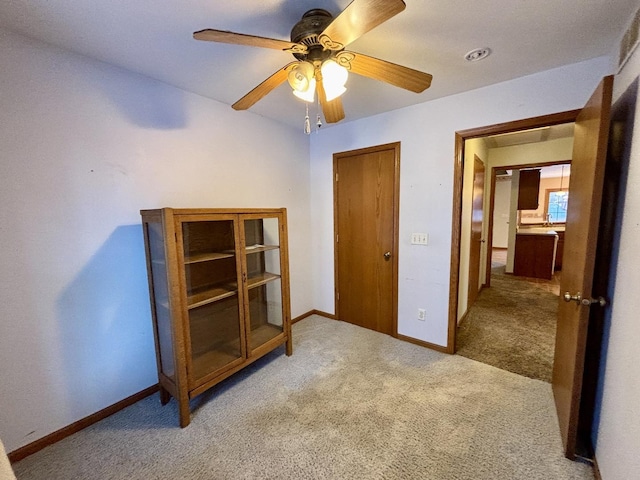 unfurnished bedroom featuring baseboards, a ceiling fan, and light colored carpet