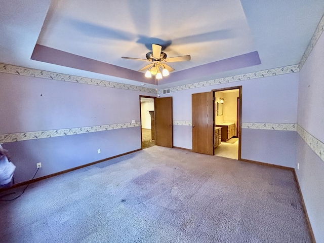 unfurnished bedroom with baseboards, a raised ceiling, visible vents, and light colored carpet