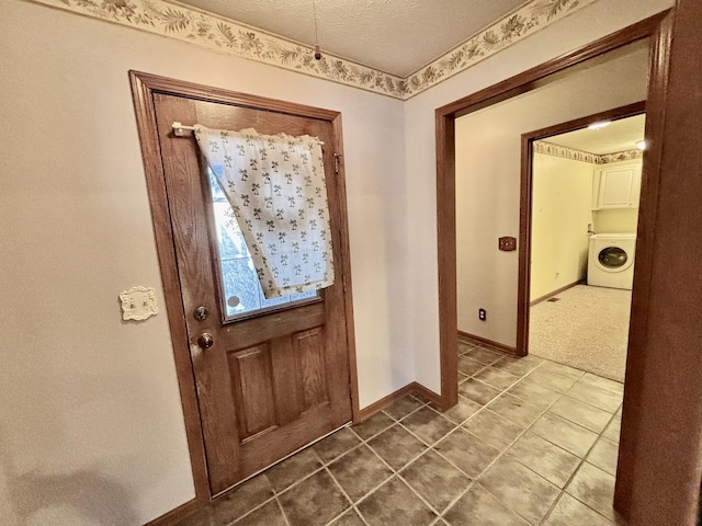 foyer entrance with tile patterned flooring, baseboards, washer / clothes dryer, and a textured ceiling