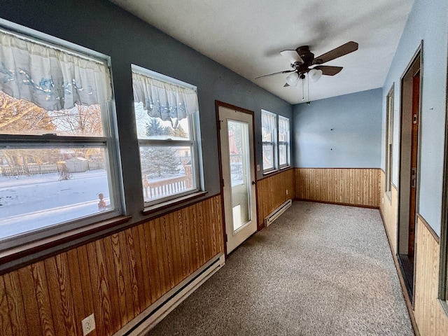 unfurnished sunroom with a ceiling fan and baseboard heating