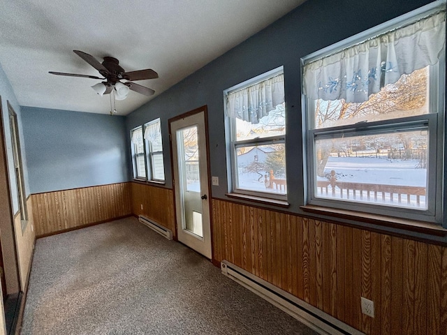 spare room featuring light carpet, a wainscoted wall, wooden walls, and a baseboard heating unit