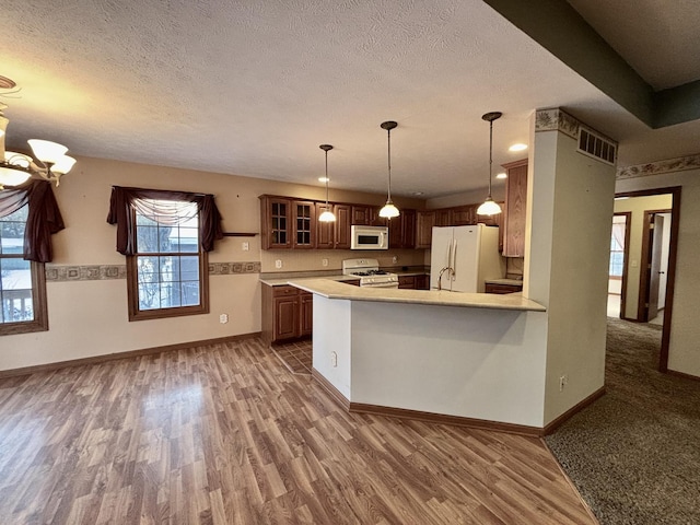 kitchen featuring light countertops, visible vents, glass insert cabinets, white appliances, and a peninsula